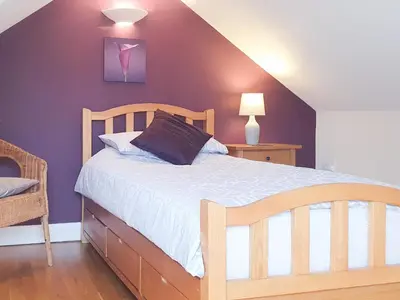 a bedroom with a bed and a purple wall at Beudy Bach-Oh5 in Dihewid