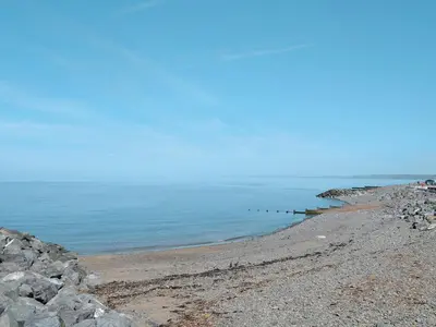 a rocky beach with a row of posts in the water at The Glen in Devils Bridge