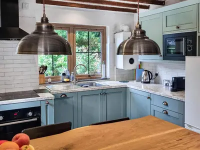 a kitchen with blue cabinets and a wooden table at The Glen in Devils Bridge