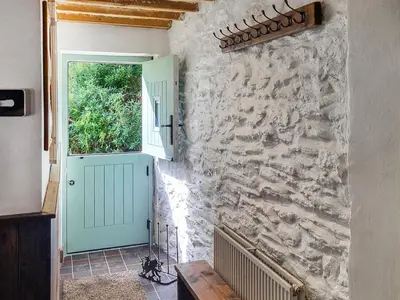 a hallway with a door and a stone wall at The Glen in Devils Bridge