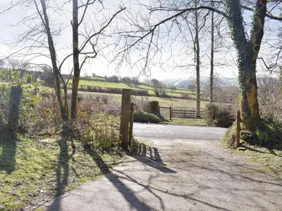 a gate on a dirt road with trees and a fence at Tynlon Villa in Bronant