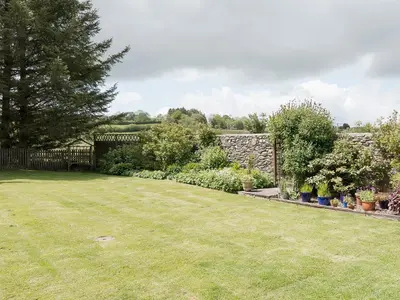 a yard with a stone wall and a garden at Yr Hen Stabl in Tregaron