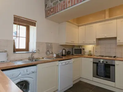 a kitchen with white cabinets and a dishwasher at Yr Hen Stabl in Tregaron
