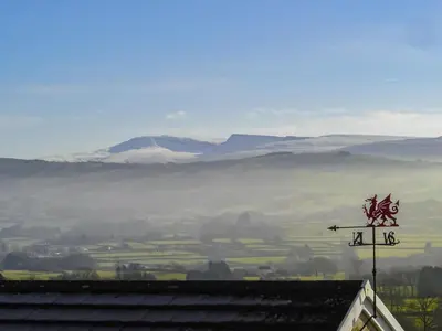 a sign on top of a roof with mountains in the background at Penybryn in Llansadwrn