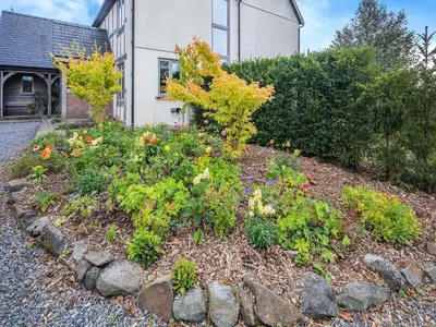 a garden with flowers in front of a house at Field View in Cynghordy