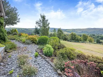 a garden with flowers and bushes on a hill at Field View in Cynghordy