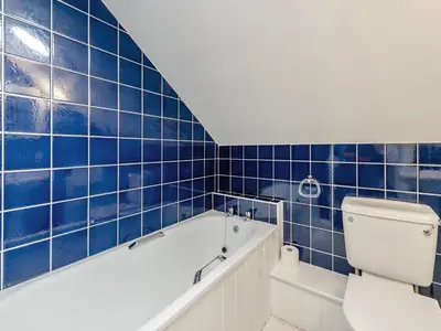 a blue tiled bathroom with a tub and a toilet at Rhyblid Fach in Myddfai