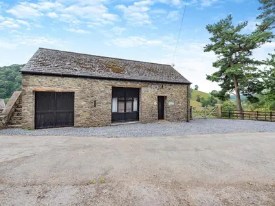 a stone barn with a driveway in front of it at Rhyblid Fach in Myddfai