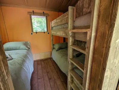 a room with two bunk beds and a window at Luxury Safari Tent with Hot Tub in Ancient Woodland in Acton Scott