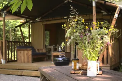 a wooden table with a vase of flowers on it at Luxury Safari Tent with Hot Tub in Ancient Woodland in Acton Scott