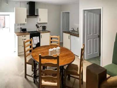 a kitchen with a wooden table and chairs in a room at Crogen Coach House - Oqr in Llandrillo