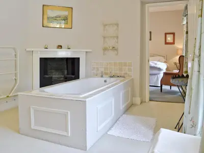 a white bath tub in a room with a fireplace at Crogen Wing in Llandrillo