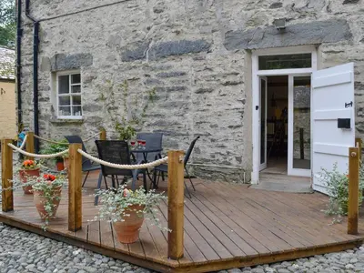 a wooden deck with a table and chairs and a building at Crogen Wing in Llandrillo