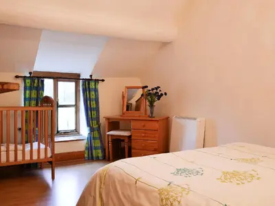 a bedroom with a bed and a dresser and a window at Hen Hafod in Llanfor