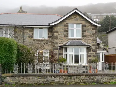 a stone house with a fence in front of it at Barreg in Barmouth
