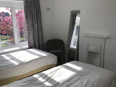 a bedroom with two beds and a chair and a window at Barreg in Barmouth