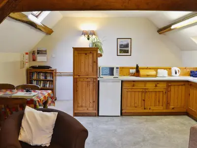 a kitchen with wooden cabinets and a white refrigerator at Erw Goed Hen Stabl in Arthog