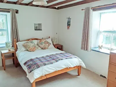 a bedroom with a bed and two windows at Erw Goed Hen Stabl in Arthog