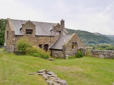 an old stone house on top of a field at Erw Goed Old Barn in Arthog