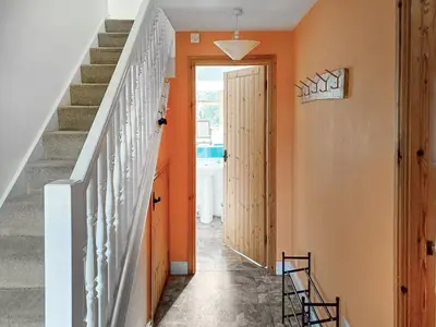 a hallway with orange walls and stairs at Erw Goed Old Barn in Arthog