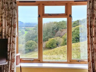 a window with a view of a hill seen through it at Erw Goed Old Barn in Arthog