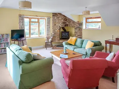 a living room with couches and chairs and a tv at Erw Goed Old Barn in Arthog