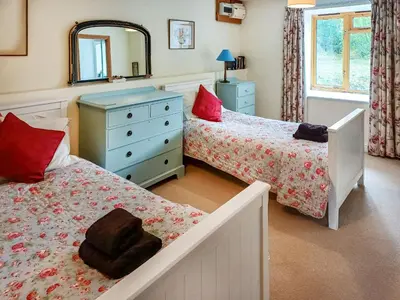 a bedroom with two beds and a dresser and a mirror at Erw Goed Old Barn in Arthog