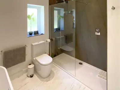 a bathroom with a shower and a toilet and a tub at Cae-Fadog Fach in Barmouth