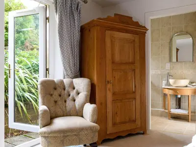 a bathroom with a chair and a sink and a mirror at Treetops in Fairbourne