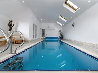 a swimming pool with blue water in a building at Treetops in Fairbourne