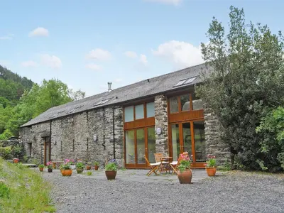a stone house with a table and chairs in front of it at Hendre Barn Mawr in Abergynolwyn