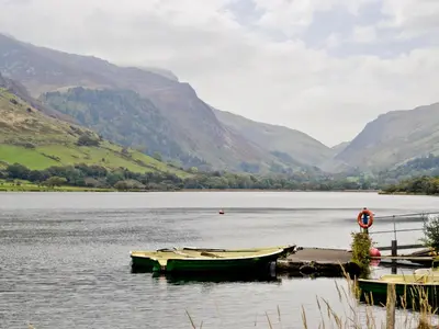 two boats are docked on the shore of a lake at Hendre Barn Mawr in Abergynolwyn