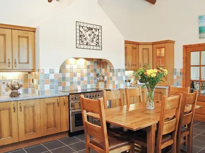 a kitchen with a wooden table and wooden chairs at Ysgubor in Harlech