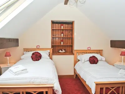 two beds in a room with red roses on them at Ysgubor in Harlech