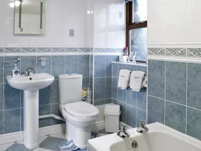 a bathroom with a toilet and a sink and a tub at Ysgubor in Harlech
