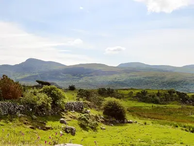 a field of green grass with mountains in the background at Beudy Hen in Harlech