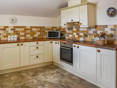 a kitchen with white cabinets and a microwave at Beudy Hen in Harlech