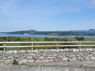 a stone wall with a fence and a lake at The Barn in Talsarnau