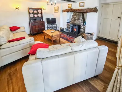 a living room with two white couches and a fireplace at Fedwr Gog Cottage in Llangwm