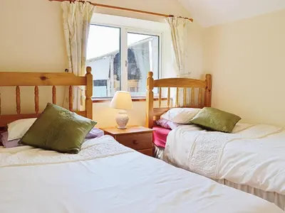 two beds in a room with a window at Fedwr Gog Cottage in Llangwm