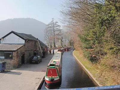 a group of boats in a canal next to a building at Fedwr Gog Cottage in Llangwm