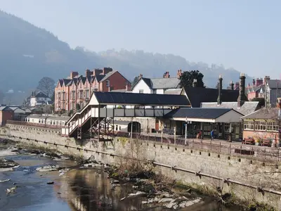 a town with a river and buildings and a bridge at Fedwr Gog Cottage in Llangwm