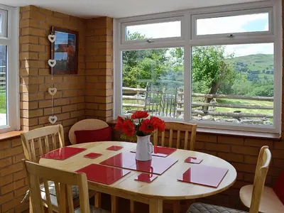 a dining room table with a vase of flowers on it at Fedwr Gog Cottage in Llangwm