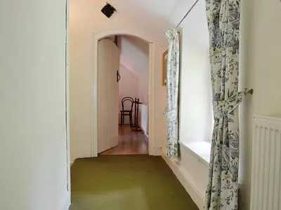 a hallway with a green floor and an open door at Fedwr Gog Cottage in Llangwm