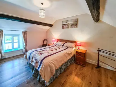 a bedroom with a bed and two lamps on a night stand at Fedwr Gog Cottage in Llangwm