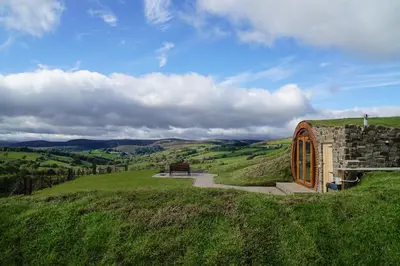 a small building on a grassy hill with a bench at Foxes View in Rhayader