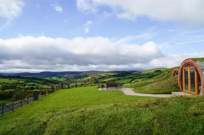 a building on a grassy hill with a pathway at Foxes View in Rhayader