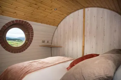 a bedroom with a bed and a round window at Foxes View in Rhayader
