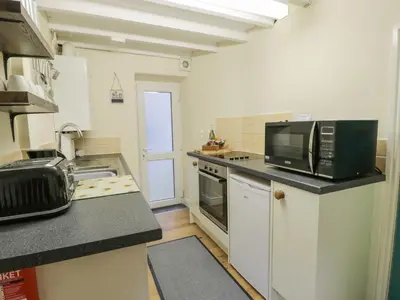 a small kitchen with a microwave and a stove at 5 Tai Isa in Barmouth