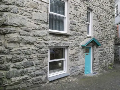a stone building with a blue door and a window at 5 Tai Isa in Barmouth